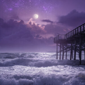 Playa de cielo violeta, con un muelle.